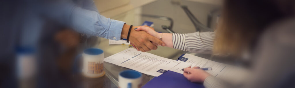 Two business solicitors shaking hands over legal documents