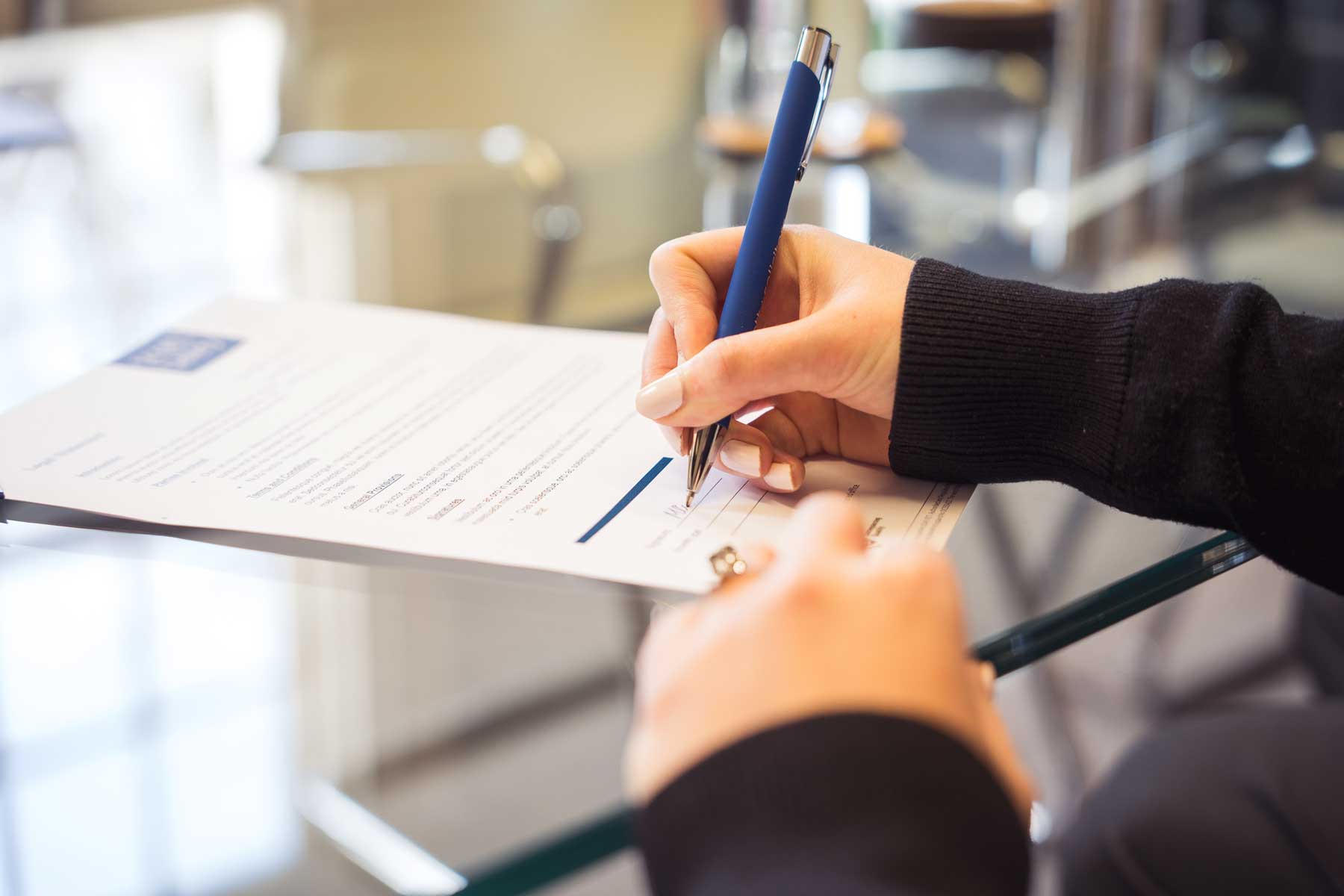 Woman with engagement ring on signs pre-nuptial agreement