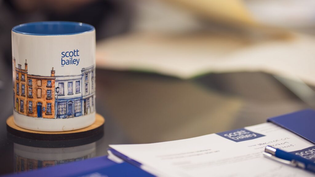 A Scott Bailey branded mug on a table in front of a legal document